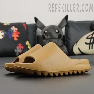 Side angle view of Yeezy Slides ‘Ochre’ on black sofa with plush toys