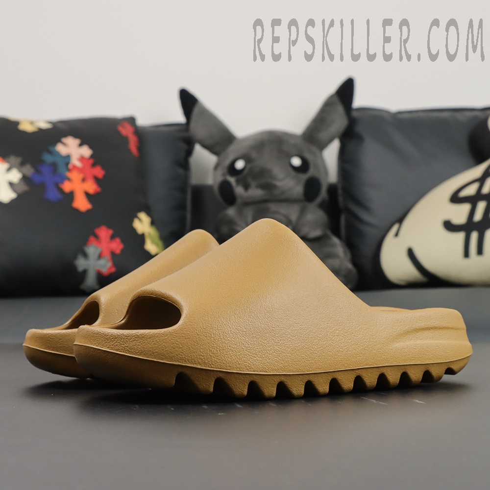 Side angle view of Yeezy Slides ‘Ochre’ on black sofa with plush toys