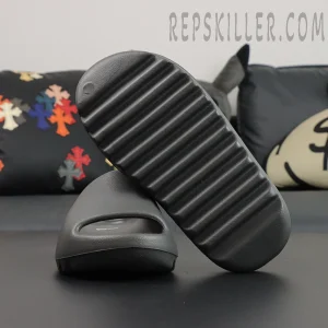 Yeezy Slides ‘Granite’ pair in lifestyle setting on black sofa