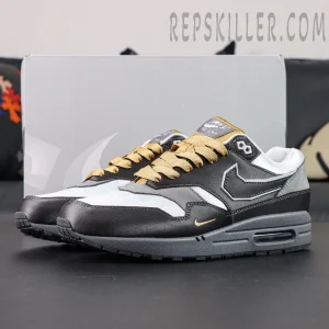 Air Max 1 “Low Poly - Big Head Mode” side view featuring black and grey upper with gold laces and futuristic detailing.
